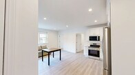 Located at 804 Main St in Willimantic, CT, this two-bedroom, one-bathroom unit offers a clean, modern aesthetic throughout its efficiently designed single-floor layout. Light wood-tone luxury vinyl flooring flows consistently across all rooms, complementing the crisp white walls and trim that give the space a bright, contemporary feel.

The open kitchen and living area serves as the heart of the unit. The kitchen is well-appointed with white shaker-style cabinetry, light quartz countertops, and a full suite of stainless steel appliances including a range, over-the-range microwave, and dishwasher. The adjacent living area benefits from a bank of large windows with roller shades, letting in generous natural light and offering views of the surrounding Willimantic streetscape.

Both bedrooms are comfortably sized with clean white walls and ample natural light from individual windows. The primary bedroom provides a quiet, versatile space, while the second bedroom features two built-in desks, making it well-suited as a home office or study. 

The bathroom is finished with neutral large-format tile flooring and features a walk-in shower with a clean white surround, offering a functional and tidy space. Throughout the unit, the minimalist design and updated finishes create a cohesive, move-in-ready environment.