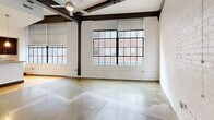 This 960 sq ft loft apartment showcases a blend of modern amenities and industrial charm. The open-concept living area boasts high ceilings with exposed wooden beams and large windows, flooding the space with natural light. The kitchen features sleek stainless steel appliances, dark wood cabinetry, and granite countertops. The bedroom, measuring 140 sq ft, offers ample space and storage. Two well-appointed bathrooms feature contemporary fixtures and finishes. Hardwood floors throughout add warmth, while a dedicated laundry area with stacked washer and dryer provides convenience. The apartment's layout maximizes space efficiency, creating a stylish urban retreat in the heart of Winston-Salem.