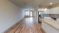 This well-appointed two-story residence offers a thoughtfully designed layout that balances functionality with modern aesthetics. The main living area is open and airy, featuring light wood-tone flooring that extends throughout the common spaces and fills the room with a warm, inviting atmosphere. Large windows fitted with blinds allow natural light to pour in, enhancing the sense of openness. A ceiling fan adds comfort to the spacious living area, which flows seamlessly toward a sliding door providing outdoor access.

The kitchen is a standout feature, showcasing white shaker-style cabinetry, granite countertops, a subway tile backsplash, and a full suite of stainless steel appliances including a refrigerator with ice maker, electric range, over-the-range microwave, and dishwasher. A kitchen island with matching granite provides additional prep space and casual dining potential, complemented by pendant lighting overhead.

The bedrooms offer plush carpeting and ample natural light, with one bedroom featuring direct outdoor access. Bathrooms are finished with granite-topped vanities and wood-look flooring. One bathroom includes a soaking tub and shower combination, while another features a walk-in shower. A walk-in closet with built-in shelving adds practical storage. Stylish panel doors and a staircase with a handrail connect the two levels seamlessly.
