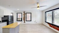 Located at 511 Maple Blvd in Kansas City, MO, this efficiently designed single-floor unit offers a thoughtful layout across a combined kitchen and living area, a hallway, and a full bathroom. Light wood-style laminate flooring runs throughout, creating a clean and cohesive look that brightens the entire space.

The open kitchen and living area serves as the heart of the unit. The kitchen is equipped with gray upper cabinetry, dark countertops, a black electric range, an over-the-range microwave, a full-size refrigerator, and a movable island with a butcher block top for added prep space. An in-unit washer is conveniently situated within the kitchen area. A ceiling fan overhead provides air circulation alongside a wall-mounted AC unit.

The living area benefits from two large windows with black frames and built-in brick accents beneath the sills, lending a distinctive industrial-residential character to the space. Natural light flows in generously, and views of the surrounding neighborhood are visible through the blinds. The white walls and clean trim keep the aesthetic bright and open.

The bathroom features a full-size tub and shower enclosure with white surrounds, a vanity with storage, and a simple, functional design. A hallway connects the main living space to the bathroom, providing a logical flow throughout the unit.