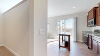 This single-floor residence offers a thoughtfully designed layout across two bedrooms and two bathrooms. The open-concept kitchen and living area serves as the heart of the home, featuring rich cherry wood cabinetry, granite countertop surfaces, a central island with a built-in sink, pendant lighting, and a full suite of stainless steel appliances including a refrigerator, microwave, and range with subway tile backsplash. Light hardwood-style flooring runs throughout the main living areas, complementing the bright, neutral color palette. Large windows fitted with horizontal blinds allow generous natural light into both the living room and kitchen, with a sliding glass door providing outdoor access.

The spacious primary bedroom features plush carpeting, a dedicated closet, and a private ensuite bathroom equipped with rich wood cabinetry, granite counters, an undermount sink, and a glass-enclosed shower. The second bedroom is similarly finished with carpet flooring and a bright window. A well-lit hallway connects the rooms, finished with clean white doors accented by gold-toned hardware. Crown molding and consistent trim details throughout contribute to the polished, cohesive aesthetic of the space.