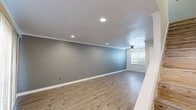 This two-story, two-bedroom, two-bathroom home offers a thoughtfully designed layout spread across two floors. The main level features an open-concept living room and kitchen area. The living room is generously sized with warm laminate wood flooring, recessed lighting, crown molding, and a ceiling fan, with vertical blinds covering a large window that fills the space with natural light. A staircase connects the two levels. The kitchen is well-equipped with white cabinetry, tile backsplash, stainless steel appliances including a dishwasher and refrigerator, a gas range, and a peninsula countertop ideal for casual dining. Light tile flooring completes the kitchen's clean, functional aesthetic. Upstairs, both bedrooms feature light hardwood-style flooring, ceiling fans, and windows with blinds that invite natural light. The primary bedroom stands out with dual bi-fold closets offering generous storage. The bathrooms are functional and clean, with one featuring a full tub, vanity with mirror cabinet, and tile flooring with chrome fixtures. Throughout the home, neutral gray and white tones create a cohesive, modern ambiance that is both practical and inviting.