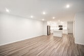 Located at 82 Beaver Spur in Moriches, NY, this single-floor unit has been thoughtfully renovated with clean, contemporary finishes throughout. The heart of the home is a bright, open kitchen outfitted with white shaker-style cabinetry, white quartz countertops, a center island, and a full suite of stainless steel appliances including a refrigerator, electric range, microwave, and dishwasher. An in-unit washer and dryer area is conveniently situated just off the kitchen. Light wood-style flooring runs through the main living and kitchen areas, lending a warm, cohesive feel to the open layout. The living area is generously proportioned, with large windows that invite natural light and views of the surrounding greenery. The bedrooms are carpeted for comfort and each features wall-unit air conditioning, baseboard heating, and ample closet space with built-in shelving and hanging rods. The bathroom is finished in a crisp, neutral palette with white cabinetry, a quartz vanity top, brushed nickel fixtures, and a glass-enclosed shower stall. Recessed lighting throughout the unit adds a polished touch, while the overall design emphasizes clean lines and a move-in-ready aesthetic.