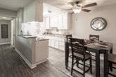 Located at 3516 Banbury Dr in Riverside, California, this single-story home offers a well-organized floor plan with distinct living, dining, kitchen, and sleeping areas. The galley-style kitchen is outfitted with white cabinetry, granite-style countertops, a gas range, a double stainless steel sink, and wood-look flooring, providing a clean and functional workspace. Adjacent to the kitchen, the dining area comfortably accommodates a full dining table and chairs, accented by a ceiling fan with light fixture and decorative wall art. The living room features wood-look flooring, a textured ceiling, and a wall-mounted ventilation system, creating a relaxed and practical space. Multiple bedrooms are finished with plush carpet, warm neutral tones, and textured ceilings. Each bedroom includes a dedicated closet, with at least one featuring a walk-in closet and direct access to an outdoor area via a sliding door. Natural light filters in through vertical-blind-covered windows. The bathroom includes a vanity with a speckled countertop, an undermount sink, and a well-lit mirror. Throughout the home, consistent use of neutral wall colors and wood-look flooring in key areas ties the spaces together cohesively.