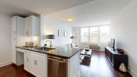 Located at 65 Bay St in Jersey City, NJ, this single-floor residence offers a clean, contemporary design with a cohesive open layout and rich hardwood flooring throughout. The open-concept kitchen flows seamlessly into the living area, featuring white shaker cabinetry, dark granite countertops, stainless steel appliances including a range and dishwasher, and a peninsula that doubles as a casual dining space. The living room is bright and inviting, anchored by large windows that frame urban views of the Jersey City skyline, allowing generous natural light to fill the space. The bedroom continues the home's refined aesthetic, with the same hardwood floors, a large window with city views, and ample closet space providing generous storage. The bathroom is finished with large-format tile flooring, a marble-surround glass-enclosed walk-in shower, and a white vanity with a stone countertop. Throughout the residence, the white walls and neutral palette create a bright, airy ambiance, while the consistent use of quality materials and modern fixtures lend a polished, urban feel. The layout is efficient yet comfortable, making excellent use of space while maintaining an open and uncluttered atmosphere ideal for contemporary city living.