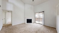 Located at 14300 Tandem Blvd in Austin, TX, this one-bedroom, one-bathroom multi-level home spans three floors and offers a thoughtfully designed layout with generous living space throughout. The main level serves as the heart of the home, featuring a spacious living area with soaring vaulted ceilings, a classic fireplace, and plush carpeting. A sliding glass door opens to a private balcony, filling the room with natural light and providing outdoor access. Adjacent to the living area, the kitchen is outfitted with white cabinetry, dark countertops, and dark hardwood-style flooring, offering a clean and functional workspace. A staircase with a white-painted railing leads up to a loft-style open area — a versatile space with angled ceilings, a ceiling fan, and a window that brings in additional natural light. The bedroom is a well-proportioned retreat featuring carpet flooring, a ceiling fan, and a closet. The bathroom features a dual-sink vanity with light stone countertops, white cabinetry, and wood-style flooring. A dedicated laundry area adds everyday convenience. With its dramatic vertical architecture, multi-level design, and bright, neutral palette throughout, this home offers a distinctive and functional living experience in Austin, TX.