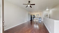 Located in San Antonio's 78258 zip code, this two-bedroom, two-bathroom two-story home offers a well-designed layout across two levels. The main living area features rich hardwood-style flooring and a ceiling fan overhead, creating a bright, open atmosphere. The kitchen flows seamlessly into the living space and is equipped with white cabinetry, granite-topped counters, a large center island with pendant lighting, black appliances, and open shelving — ideal for both cooking and entertaining. A half-wall partition adds definition between the kitchen and living areas without sacrificing the open feel. Both bedrooms are carpeted and include ceiling fans, with the primary bedroom offering generous proportions and large windows that invite natural light and neighborhood views. Each bedroom benefits from dedicated closet space, including a walk-in closet with wire shelving systems. The two bathrooms feature wood-style flooring, grey cabinetry with dark countertops, and a tub-shower combination. A dedicated laundry area and ample storage via four closets add practicality. Carpeted staircases with white handrails connect the levels. The private balcony offers open views of the surrounding landscape, including a distant horizon — a standout feature of this well-appointed home.