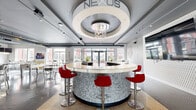 Nexus Play at 900 Luxor Lane in Norristown, PA is a single-floor entertainment and social amenity space spanning a generously sized footprint designed to encourage community engagement and leisure. The space is divided into distinct yet interconnected zones, each with its own character and purpose.

At the heart of the venue sits a striking circular bar with a granite-textured base and a smooth white countertop, surrounded by bold red swivel bar stools. Above it, a dramatic tiered ceiling medallion with an ornate chandelier serves as a commanding architectural focal point. Adjacent to the bar, a mounted flat-screen TV and a textured accent wall add a modern, polished feel, while sculptural wall art contributes to the space's contemporary aesthetic.

The lounge entry corridor features herringbone-patterned flooring, plush modular seating in dark upholstery, pendant lighting, and abstract wall art set against muted purple walls, creating a welcoming and sophisticated arrival experience.

The game room area transitions to an industrial aesthetic, with exposed ductwork along the ceiling and large windows that flood the space with natural light and views of the surrounding courtyard. A billiards table with a rich purple felt surface and a foosball table are prominent features here, offering ample room for recreation.

Large glass doors open directly to an outdoor patio, seamlessly connecting the interior to the exterior environment and enhancing the open, airy feel of the entire space.