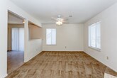 This single-floor home offers a practical and comfortable layout designed for everyday living. The living area is generously sized, featuring warm neutral-toned carpet, a ceiling fan with integrated lighting, and multiple windows dressed with horizontal blinds that allow ample natural light to fill the space. The open sightline between the living area and kitchen creates a connected, airy feel throughout the common spaces.

The kitchen is equipped with ample upper and lower cabinetry featuring wood-trimmed white doors, a double stainless steel sink, a dishwasher, an electric range, and a full-size refrigerator. Light tile flooring adds a clean, durable surface to the cooking area, which connects seamlessly to the living space via an open passthrough layout.

The bedrooms are carpeted and each feature ceiling fans with lighting, as well as windows that bring in natural light. One bedroom includes access to a walk-in closet, providing useful storage. Textured ceilings are present in several rooms, adding a classic finish throughout.

The bathroom includes a tub and shower combination with glass sliding doors, a single-sink vanity with wood-trimmed cabinetry, a large mirror, and tile flooring, offering a clean and functional design overall.