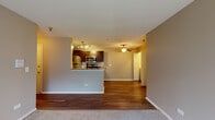 This single-floor residence at 355 N Oakhurst Dr in Aurora, Illinois offers a well-designed open-concept layout that seamlessly connects the kitchen and living areas. The kitchen is a standout feature, equipped with stainless steel appliances including a refrigerator, range, and microwave, complemented by rich dark cabinetry, a subway tile backsplash, and granite-style countertops. A peninsula with a built-in sink provides additional workspace and casual seating, making it a functional and stylish hub of the home. Track lighting overhead ensures the kitchen is well-lit throughout.

The adjoining living area features warm hardwood-style flooring that transitions to plush carpet in the bedroom spaces, creating a comfortable and cohesive feel. A ceiling fan anchors the main living space, adding both comfort and character. The bedrooms are generously proportioned, with neutral tones and natural light from windows overlooking greenery. At least one bedroom includes a spacious walk-in closet with built-in shelving for ample storage.

A dedicated laundry area with a washer and dryer is conveniently located within the unit. The bathroom features a full soaking tub with a classic surround. Overall, the space presents a clean, functional aesthetic suitable for comfortable everyday living.