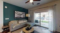 This single-floor residence offers a thoughtfully designed open-concept layout that seamlessly connects the kitchen, dining, and living areas. The kitchen is outfitted with dark espresso cabinetry, granite countertops, a subway tile backsplash, and a full suite of stainless steel appliances. A central island with pendant lighting above provides additional prep space and casual bar seating for two. Wood-look flooring flows throughout the main living areas, adding warmth and continuity to the space. The living room serves as a welcoming focal point, highlighted by a bold teal accent wall, a ceiling fan, and large sliding glass doors that open onto a private balcony overlooking a landscaped exterior. The two bedrooms are carpeted for comfort and each feature ceiling fans and generously sized windows that allow ample natural light to fill the rooms. The full bathroom includes dark wood cabinetry with granite countertops, wood-look flooring, and a full soaking tub and shower combination. Throughout the residence, a neutral color palette is complemented by carefully chosen design accents, creating a cohesive and inviting atmosphere that balances modern finishes with everyday functionality.