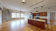 Located at 382 Cherry St in downtown Macon, GA, this 2-bedroom, 2-bathroom unit blends industrial character with modern finishes across a single, well-organized floor. The open-concept kitchen and living area serves as the heart of the home, showcasing warm hardwood floors, soaring ceilings with crown molding, and abundant natural light from large windows. The kitchen is outfitted with rich wood cabinetry, granite countertops, stainless steel appliances, and a substantial island with a built-in sink — ideal for both cooking and entertaining. Track lighting and pendant fixtures add a contemporary touch overhead. Each bedroom features hardwood floors, a ceiling fan, and generous natural light. The primary bedroom is spacious, complete with a dedicated closet, while a second closet provides additional storage. A standout design element throughout is the exposed concrete accent walls, lending an authentic urban-loft aesthetic. Both bathrooms are finished with granite-topped wood vanities and stone tile flooring, with one featuring a walk-in shower. A dedicated laundry room with wire shelving and washer/dryer hookups adds everyday convenience. This unit offers a compelling mix of industrial charm and refined finishes in the heart of Macon.