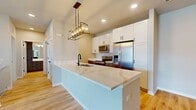 This contemporary townhouse in Elgin, IL offers 1550 square feet of living space across two floors. The lower level features a spacious garage with ample storage potential. Ascending to the main floor, you'll find an open-concept living area that combines the kitchen, dining, and living spaces. The kitchen boasts sleek white cabinetry, stainless steel appliances, and a generous island with a sink, perfect for meal preparation and casual dining.

Two bedrooms, including the 170 square foot primary bedroom, provide comfortable sleeping quarters. Both bathrooms feature modern fixtures, with one showcasing a glass-enclosed shower and the other a tub-shower combination. Light wood flooring in the bathrooms and living areas adds warmth to the space.

The townhouse includes an in-unit laundry room with a stacked washer and dryer, enhancing convenience. Large windows throughout allow natural light to flood the rooms, while a balcony offers outdoor space and views of the surrounding community. Neutral wall colors and carpeting in the bedrooms create a blank canvas for personalization. This well-designed home combines functionality with contemporary style, ideal for modern living.