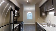 Located at 1751 Dogwood Drive in Charleston, South Carolina, this single-story home offers a well-designed layout with thoughtful finishes throughout. The kitchen is a standout feature, equipped with dark espresso cabinetry that provides ample storage, light granite countertops, and a full suite of stainless steel appliances including a built-in microwave, electric range, and refrigerator. The kitchen flows seamlessly into a dedicated dining area, which is highlighted by a stylish chandelier and a window dressed with blinds that allows natural light to filter into the space. The wood-look flooring runs throughout, adding warmth and continuity to the interior. The neutral wall tones and textured ceilings contribute to a clean, modern aesthetic. The single-floor layout offers convenient accessibility and an efficient use of space, making it an ideal setting for comfortable everyday living. The home's location in Charleston, SC places it within reach of the area's rich culture, dining, and outdoor amenities.