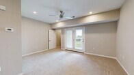 Located at 998 E Tracker Rd in Nixa, Missouri, this single-floor unit offers a thoughtfully arranged layout with a kitchen, bathroom, and closet. The main living area is finished with plush wall-to-wall carpet and neutral taupe-toned walls, creating a calm and welcoming atmosphere. A ceiling fan with recessed lighting keeps the space comfortable, while a set of French doors with white plantation shutters brings in natural light and provides access to an outdoor area with pleasant views. The galley-style kitchen is efficiently designed and well-appointed, featuring white shaker-style upper cabinets, two-toned lower cabinetry, white quartz countertops, and a classic subway tile backsplash. Stainless steel appliances — including a full-size refrigerator, electric range, over-the-range microwave, and dishwasher — complement the light hardwood-style flooring that runs throughout the kitchen. The bathroom continues the clean, modern aesthetic with white cabinetry, a white countertop vanity, tile flooring in a light stone finish, and brushed nickel hardware accents. A dedicated closet adds practical storage to the space. Overall, the unit presents a clean, move-in-ready environment with consistent modern finishes and a functional, efficient floor plan.