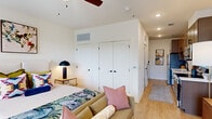Located at 103 East 2nd Street in Richmond, VA, this one-bedroom, one-bathroom unit offers a well-designed single-floor layout that maximizes every inch of its intimate footprint. The spacious bedroom serves as the heart of the home, featuring warm light hardwood flooring, a ceiling fan, recessed lighting, and generous double-door closets that provide ample storage. A window allows natural light to filter in, enhancing the bright, airy ambiance of the space.

The galley-style kitchen is efficiently appointed with stainless steel appliances — including an electric range, microwave, and refrigerator — complemented by sleek taupe cabinetry, white countertops, and a classic subway tile backsplash. The layout allows for smooth workflow despite the compact configuration.

The bathroom features a clean, modern aesthetic with white subway tile surrounding the tub-shower combination, matte black hardware and fixtures, wood-look flooring, and a contemporary floating vanity with an undermount sink.

Throughout the unit, light hardwood flooring creates visual continuity, while white walls provide a neutral backdrop. The overall design balances practicality with contemporary style, making this Richmond unit a functional and inviting urban residence.