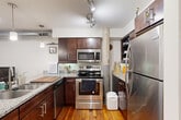 Located at 1111 Hawthorne Ln in Charlotte, NC, this two-floor loft-style space blends industrial character with comfortable living across a generous layout. The main floor accommodates the primary living areas, including a combined kitchen and living room, two bathrooms, and a dedicated office, while the upper level hosts the private bedroom retreat.

The kitchen is a standout feature, offering rich dark-wood cabinetry, granite countertops with a breakfast bar, stainless steel appliances, and warm hardwood flooring — all anchored by a rustic structural column that nods to the building's industrial heritage. The adjoining living room provides a relaxed atmosphere with recessed lighting, a ceiling fan, clerestory windows that draw in natural light, and rich hardwood floors throughout.

The office space makes a striking impression with soaring ceilings, dramatic floor-to-ceiling industrial steel-frame windows, and an exposed brick wall that floods the room with natural light and urban character.

The bedroom features a wood-beam ceiling with a ceiling fan, hardwood floors, and clerestory windows. Exposed structural elements continue the loft aesthetic. Both bathrooms are clean and functional, with tile flooring and classic fixtures. The upper-floor bathroom is tucked beneath the sloped roofline, adding a cozy, architectural touch to the space.