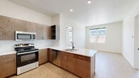 Located at 217 E Campbell St in Edmond, Oklahoma, this modern 2-bedroom, 3-bathroom residence offers a thoughtfully designed single-floor layout with clean lines and contemporary finishes throughout. The kitchen is a standout feature, equipped with stainless steel appliances including a French door refrigerator, over-the-range microwave, and electric range. Rich, warm-toned wood cabinetry extends to the ceiling, complemented by white quartz countertops, a classic subway tile backsplash, and light hardwood-style flooring that adds warmth and continuity. Both bedrooms are carpeted for comfort and feature ceiling fans, bright white walls, and windows offering views of the surrounding Edmond streetscape. The primary bedroom is a well-proportioned retreat that includes a walk-in closet with wire shelving and direct access to a private bathroom. The bathrooms are finished with floating wood vanities, white countertops, black matte fixtures, rounded rectangular mirrors with backlit vanity lighting, and tiled soaking tub surrounds. Hardwood-style flooring carries through the bathrooms, tying the aesthetic together. The overall ambiance is fresh, modern, and move-in ready, with a neutral palette that offers versatile styling potential.