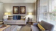 Located at 801 Elmcroft Blvd in Rockville, Maryland, this single-floor residence offers a thoughtfully designed layout with modern finishes throughout. The living room is warm and inviting, featuring plush carpeting, crown molding, and large windows that allow natural light to fill the space, complemented by tasteful neutral tones. The galley-style kitchen is well-appointed with white shaker cabinetry, granite countertops, a classic subway tile backsplash, stainless steel appliances, and durable wood-look flooring — a functional and stylish space for everyday cooking. The bedroom is generously sized with soft carpeting, a ceiling fan, ample natural light from large windows, and direct access to a walk-in closet for convenient storage. The bathroom features a dual-sink vanity with white cabinetry and countertops, framed mirrors, and wood-look flooring that extends into the hallway, creating a clean and cohesive aesthetic. A dedicated in-unit laundry area houses a full-sized washer and dryer with wire shelving above for additional storage. Throughout the residence, a consistent palette of warm grays, whites, and modern fixtures creates a cohesive and comfortable living environment.