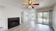 Located at 1595 S Old Orchard Ln in Lewisville, TX, this single-story one-bedroom, one-bathroom unit offers a well-organized layout with clean, modern finishes throughout. Light wood-look flooring runs continuously across the space, complementing the crisp white walls and creating a bright, cohesive feel.

The combined kitchen and living room serves as the heart of the unit. The living area features a striking black tile-surround fireplace, a ceiling fan with light fixture, and a sliding glass door that opens to a private balcony with outdoor views. The kitchen is equipped with stainless steel appliances—including a refrigerator, range, and microwave—white cabinetry, a tile backsplash, and a white countertop pass-through that connects the kitchen to the living space.

The bedroom is a comfortable, well-proportioned room with its own ceiling fan, a window for natural light, and direct access to both the closet and the bathroom. The bathroom features a white vanity with ample cabinetry, a large mirror with Hollywood-style lighting, and wood-look flooring. A dedicated laundry area includes washer/dryer hookups and wire shelving for additional storage. Textured ceilings are found throughout the unit, adding a consistent design element across every room.