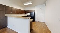 Located at 2675 W Agate Ave in Las Vegas, NV, this 1-bedroom, 1-bathroom residence offers a thoughtfully designed layout across a single floor. The open-concept kitchen is a standout feature, showcasing rich dark espresso cabinetry, granite countertops, a peninsula with a breakfast bar, and black appliances including a refrigerator and range. Wood-style flooring runs throughout the main living areas and kitchen, adding warmth and continuity to the space. A skylight above the kitchen brings in additional natural light, complementing the ceiling fan and pendant lighting in the living area. The bedroom is carpeted for comfort, features a ceiling fan, and is brightened by a large window with exterior views and blinds for privacy. The bathroom continues the home's refined aesthetic with matching dark cabinetry, granite countertops, a large vanity mirror, and wood-style flooring. A dedicated closet and hallway provide practical storage and flow between rooms. Clean white walls throughout create a bright, neutral backdrop that enhances the overall sense of openness in this efficiently designed Las Vegas home.