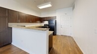 Located at 2675 W Agate Ave in Las Vegas, NV, this 1-bedroom, 1-bathroom residence offers a thoughtfully designed layout across a single floor. The open-concept kitchen is a standout feature, showcasing rich dark espresso cabinetry, granite countertops, a peninsula with a breakfast bar, and black appliances including a refrigerator and range. Wood-style flooring runs throughout the main living areas and kitchen, adding warmth and continuity to the space. A skylight above the kitchen brings in additional natural light, complementing the ceiling fan and pendant lighting in the living area. The bedroom is carpeted for comfort, features a ceiling fan, and is brightened by a large window with exterior views and blinds for privacy. The bathroom continues the home's refined aesthetic with matching dark cabinetry, granite countertops, a large vanity mirror, and wood-style flooring. A dedicated closet and hallway provide practical storage and flow between rooms. Clean white walls throughout create a bright, neutral backdrop that enhances the overall sense of openness in this efficiently designed Las Vegas home.