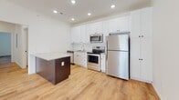 Located at 1000 Hartman Ct in Saint Peters, Missouri, this single-story residence offers a clean, contemporary design throughout. The open living area is finished with light wood-look flooring and features a ceiling fan and a sliding glass door framed by vertical blinds, allowing abundant natural light to pour in and providing access to an outdoor space.

The kitchen is well-equipped for everyday living, showcasing white shaker-style cabinetry extending to the ceiling, granite countertops, a subway tile backsplash, stainless steel appliances including a range, microwave, and refrigerator, and a contrasting dark-base island with additional granite counter space. Recessed lighting illuminates the area effectively.

The bedrooms offer a comfortable retreat, with plush carpeting and windows that invite natural light. Bathrooms include one with a walk-in shower enclosed by sliding glass doors and another featuring a full soaking tub with shower combination, both finished in white with wood-look flooring. A dedicated laundry area houses a full-size washer and dryer with overhead shelving. The overall palette is neutral and bright, creating a welcoming, move-in ready environment.