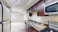 This single-floor 1-bedroom, 1-bathroom unit offers a practical and comfortable layout designed to maximize everyday living. The open-concept living and dining area features plush carpet flooring, warm neutral-toned walls, and natural light streaming through white-slatted blinds. An elegant chandelier anchors the dining space, adding a touch of character to the open layout.

The kitchen is outfitted with rich, dark espresso cabinetry, a double-basin stainless steel sink, dark laminate countertops, and stainless steel appliances including a gas range and over-the-range microwave. Wood-style flooring in the kitchen and hallway provides a clean contrast to the carpeted living areas.

The bedroom is a calm, understated retreat with soft carpet, warm beige walls, and a window that allows in natural light. The full bathroom features a dark wood vanity with a white countertop, a well-lit mirror with overhead vanity lighting, wood-look tile flooring, and a shower-tub combination. A dedicated in-unit laundry area accommodates a full-size side-by-side washer and dryer with overhead shelving for added storage. The hallway efficiently connects all areas of the unit, reinforcing a cohesive and functional floor plan throughout.
