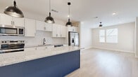 Located in Sugar Hill, GA, this 2-bedroom, 1-bathroom single-story home offers a thoughtfully designed open-concept layout that maximizes its comfortable footprint. The kitchen is a standout feature, boasting a large island with a bold navy blue base and speckled granite countertop, white shaker cabinets, a classic subway tile backsplash, and a full suite of stainless steel appliances including a refrigerator with ice maker, dishwasher, range, and microwave. Pendant lighting above the island adds a modern industrial touch. The kitchen flows seamlessly into the living area, which features light wood-style flooring, recessed lighting, and a ceiling fan for year-round comfort. Natural light filters in through windows with blinds, creating a bright and airy ambiance. The primary bedroom features wood-style flooring, a ceiling fan, and ample natural light, while the second bedroom is finished with plush neutral carpet and its own ceiling fan. The bathroom is clean and functional, with a granite-topped vanity, white cabinetry with brushed nickel hardware, a tiled shower/tub combination, and matching wood-style flooring. Throughout, the home maintains a fresh, modern aesthetic with neutral tones and crisp white trim.