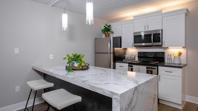 Our kitchens feature a spacious marble-style breakfast bar, stainless steel appliances, and elegant pendant lighting. - Elon Winter Park Apartments