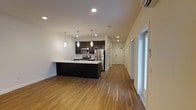Located at 36 Pine Street in Poughkeepsie, NY, this two-bedroom, two-bathroom residence offers a thoughtfully designed single-floor layout with modern finishes throughout. The open-concept living and kitchen area serves as the heart of the unit, where warm hardwood-style flooring flows seamlessly from room to room, creating a cohesive and inviting atmosphere. The contemporary kitchen is a standout feature, equipped with stainless steel appliances including a French door refrigerator, range, and microwave. Dark espresso cabinetry contrasts elegantly with the light countertops, while a peninsula island provides additional prep space and casual seating. Pendant lighting above the island adds a stylish focal point, complemented by recessed lighting throughout for bright, even illumination. A wall-mounted mini-split system ensures efficient climate control year-round. Large glass panels near the entryway invite natural light into the space, enhancing its clean, airy feel. The unit's layout offers a practical corridor connecting the living areas to the bedrooms and bathrooms, providing a clear separation between social and private spaces. Overall, this residence combines functional design with modern aesthetics, making it a comfortable and stylish home in the heart of Poughkeepsie.