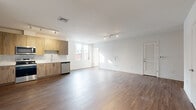 Located at 808 Chapel Street in the heart of New Haven, CT, this modern residence offers a thoughtfully designed single-floor layout with three bedrooms and three bathrooms. The open-concept kitchen and living area serves as the centerpiece of the home, featuring warm wood-tone cabinetry, white quartz countertops, a subway tile backsplash, and a full suite of stainless steel appliances including a refrigerator, dishwasher, range, and microwave. Track lighting and large windows allow natural light to flow freely throughout the space, complementing the rich hardwood-style flooring that runs continuously across the unit. The living area is spacious and bright, with clean white walls and city views visible through generously sized windows. Each bedroom is well-proportioned, with some rooms offering floor-to-ceiling windows that frame urban New Haven views, and at least one bedroom includes an open closet with built-in shelving. The three bathrooms maintain the home's modern aesthetic, featuring wood-tone vanities with white countertops, large mirrors, and wood-look tile flooring. One bathroom includes accessibility grab bars. A dedicated closet provides additional storage. The overall ambiance is clean, contemporary, and move-in ready.