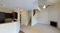 This well-appointed two-story home offers three bedrooms and two and a half bathrooms across a thoughtfully designed floor plan. The main level features an open-concept layout where the living area flows seamlessly into the kitchen. The living room is finished with warm carpeting and wood-look flooring at the entry, and is topped by soaring ceilings that extend into the upper level, enhancing the sense of openness and airiness. A ceiling fan with a light fixture is suspended above, adding both function and a casual aesthetic. The kitchen is equipped with rich dark cabinetry and granite-style countertops, offering a stylish contrast to the neutral tones throughout the home. A half bathroom is conveniently located on the main floor for guests. A staircase with carpeted treads leads to the upper level, where the three bedrooms and two full bathrooms are situated, providing privacy and separation from the main living areas. The home's neutral color palette, consistent trim work, and textured ceilings create a cohesive and inviting atmosphere throughout. The combination of practical layout, generous proportions, and quality finishes makes this a comfortable and functional home.