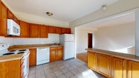 Located on Commonwealth Avenue in Allston, this single-floor residence offers a functional and comfortable layout with a cohesive design throughout. The kitchen is a standout feature, outfitted with warm honey-toned wood cabinetry, granite-style countertops, a classic subway tile backsplash, and a full suite of white appliances including a range, dishwasher, refrigerator, and over-the-range microwave. Large tile flooring grounds the kitchen space, which opens conveniently into the living area via a peninsula counter — ideal for casual dining or additional prep space. The living and dining areas are distinguished by gleaming hardwood floors that carry natural light beautifully throughout. A charming bay window arrangement in the living room invites an abundance of daylight and provides pleasant neighborhood views. The bedrooms continue the hardwood flooring theme and are bright and airy, each benefiting from multiple windows. One bedroom features a radiator unit, offering traditional heating. The bathroom is finished with full tile surround, a white vanity, and a window for natural ventilation. Additional hardwood-floored rooms provide flexible use. Overall, the space presents a clean, practical, and welcoming environment well-suited to everyday living in one of Boston's most vibrant neighborhoods.