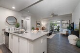 Located at 2001 S Hudson Ave in Boise, Idaho, this well-designed one-bedroom, one-bathroom residence makes smart use of its single-floor layout. The open-concept kitchen and dining area serves as the heart of the home, featuring white shaker cabinetry, stainless steel appliances including a refrigerator, electric range, and built-in microwave, along with a spacious peninsula with an undermount sink — ideal for both meal prep and casual dining. The adjoining dining nook is illuminated by a pendant chandelier, adding a refined touch. The living room offers wood-style plank flooring, a ceiling fan, and sliding glass doors that open directly onto a private patio, bringing in natural light and outdoor views. The bedroom features plush carpeting, a ceiling fan, a large window, and a stylish accent wall with geometric wallpaper. A walk-in closet provides ample storage. The full bathroom includes a dual-sink vanity with quartz countertops, recessed lighting, and a louvered-door closet. Additional conveniences include a dedicated laundry area, a hallway with extra closet space, and an entryway with built-in wall hooks. The unit's clean, modern aesthetic and functional layout make it a comfortable and practical Boise residence.