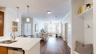 Located in Raleigh, NC, this well-appointed 2-bedroom, 4-bathroom single-story residence offers a thoughtfully designed open-concept layout finished with warm, neutral tones throughout. The kitchen is a functional centerpiece, featuring rich wood cabinetry, stainless steel appliances, a double-basin sink, and a peninsula with pendant lighting and bar seating — ideal for casual dining or entertaining. Hardwood-style flooring flows from the kitchen through the dining area and into the living room, which is bathed in natural light from multiple large windows dressed with classic plantation shutters and sheer curtains. A ceiling fan adds comfort to the airy living space. Both bedrooms are carpeted and well-sized, each equipped with ceiling fans, generous windows with outdoor views, and ample closet space — including walk-in closets outfitted with wire shelving systems. The four bathrooms are finished with tile flooring, warm wood vanities, white countertops, and framed mirrors. One bathroom features a tub/shower combination with tile surround, while another offers a sleek single-vanity design. A dedicated laundry room houses a full-size washer and dryer with built-in shelving for added storage convenience.