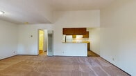 Located at 255 Coggins Dr in Pleasant Hill, CA, this single-floor residence offers a well-organized layout designed for comfortable everyday living. The living area is a standout feature, boasting soaring vaulted ceilings that create an impressive sense of height and openness. Soft carpet flooring extends throughout this space, and large sliding glass doors open to a private outdoor patio, flooding the room with natural light and providing pleasant views of surrounding greenery. An additional window further brightens the area. The kitchen is seamlessly connected to the living space via a wraparound peninsula with a light wood countertop, ideal for casual dining or food preparation. The kitchen is equipped with warm wood cabinetry, a white electric range, a refrigerator, and durable wood-look flooring that contrasts nicely with the carpeted living area. A dedicated closet area with louvered doors offers practical storage just off the main living space. The bathroom features wood-look flooring, a wood-toned vanity with a white countertop and mirror, a toilet, and a shower-tub combo with sliding glass doors. Neutral tones and textured ceilings are consistent throughout, giving the space a cohesive and understated aesthetic.