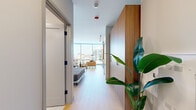Located in the heart of Chicago's vibrant Old Town neighborhood, this thoughtfully designed studio at 920 N Wells St offers a single-floor layout that maximizes every square foot with smart, modern design. A welcoming entry hallway, accented by warm wood-paneled cabinetry and light hardwood-style flooring, leads into the open-plan living and kitchen area.

The living space is immediately defined by dramatic floor-to-ceiling windows that wrap the corner of the room, flooding the interior with natural light and framing sweeping views of the Chicago skyline. The combined living area provides ample space for lounging and dining, with clean white walls and light flooring enhancing the airy ambiance.

The kitchen is a standout feature, showcasing warm wood cabinetry that extends floor to ceiling, dark stone countertops, a bold navy subway tile backsplash, and stainless steel appliances including a full-size refrigerator and built-in oven. Open shelving adds a stylish, functional touch.

The bathroom continues the refined aesthetic with large-format light stone-look tile, a glass-enclosed walk-in shower, a sleek dark vanity with an undermount sink, and a backlit frameless mirror, delivering a spa-like experience. The overall design balances functionality and contemporary elegance throughout.