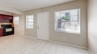 Located at 115 SW 16th St in Pompano Beach, Florida, this two-bedroom, one-bathroom single-floor unit offers a practical and well-organized layout. Light-toned tile flooring runs consistently throughout the entire space, contributing to a clean, cohesive look.

The combined living and dining area greets you upon entry, flanked by two windows that allow natural light to fill the room. The open layout provides a comfortable flow into the kitchen, which is separated by a half-wall partition. The kitchen is outfitted with rich, dark mahogany-toned cabinetry extending from floor to ceiling, complemented by a warm stone-patterned tile backsplash, a built-in sink, and black appliances including a range and refrigerator.

A hallway connects the main living area to the two bedrooms, each featuring neutral walls, tile flooring, and individual closets with bifold doors. The primary bedroom is a well-proportioned space with ample room for furnishings. The shared full bathroom includes a tub-shower combination with white subway tile surround.

The unit features textured ceilings throughout, and ceiling-mounted HVAC vents ensure year-round climate comfort — an essential in South Florida's warm climate. The layout is efficient and functional, making effective use of the available space.