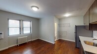 Situated on Hennepin Avenue in the heart of Minneapolis, Minnesota, this single-floor unit blends classic architectural character with modern updates throughout. Rich, warm hardwood flooring runs continuously across the main living areas, grounding the space with a timeless aesthetic.

The kitchen is a standout feature, outfitted with full-height dark wood cabinetry that provides generous storage, light countertops, and a classic white subway tile backsplash. A complete suite of stainless steel appliances — including a refrigerator, gas range, built-in microwave, and dishwasher — makes the kitchen both functional and visually cohesive.

The bedroom is a calm, well-proportioned room with neutral gray walls, natural light from a window fitted with blinds, and a cast iron radiator reflecting the building's heritage. A wall-mounted air conditioning unit ensures year-round comfort. An additional area off the main room features wire shelving, offering practical storage or closet space.

The bathroom is finished in crisp white subway tile from floor to ceiling around the tub surround, complemented by white tile flooring and a bright vanity. Natural light filters in through frosted windows, creating a clean and refreshing atmosphere. Overall, the unit offers a well-maintained, character-rich living space in a prime urban location.