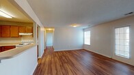 This single-floor residential unit offers a practical and well-organized layout designed for comfortable everyday living. The spacious living area is finished with warm-toned wood-look flooring that extends throughout the common spaces, creating a cohesive and inviting atmosphere. A textured ceiling adds subtle character to the open living space, which is illuminated by natural light from a window and connects seamlessly to the rest of the unit via a central hallway.

The kitchen is accessible both through a direct entryway and a pass-through window that opens to the living area, offering a connected feel. It features warm wood cabinetry, light countertops, a double-basin sink, a white electric range with a ventilation hood, and a dishwasher — providing ample storage and functionality.

The bedrooms are carpeted for comfort and each includes a window that brings in natural light and outdoor views. One bedroom features a closet with a built-in rod and shelf. The unit includes two full bathrooms, each equipped with a tub-shower combination featuring white tile surround, a vanity with storage, and wood-look flooring. Together, these spaces form a clean, functional home with a straightforward and efficient design.