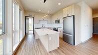 Located at 1659 N Jackson St in Milwaukee's Upper East Side, this thoughtfully designed 2-bedroom, 2-bathroom residence offers a clean, contemporary aesthetic throughout. The open-concept kitchen and living area serves as the heart of the home, featuring light wood cabinetry, white quartz countertops, a subway tile backsplash, stainless steel appliances, and a central island with pendant lighting — ideal for both everyday living and entertaining. Light-toned wood-style flooring flows throughout the main living areas, lending warmth and continuity to the space. Floor-to-ceiling windows and a corner window configuration in the living area flood the space with natural light and provide expansive views of the Milwaukee skyline and surrounding greenery, with direct access to a private balcony. The generously sized primary bedroom features large picture windows with treetop and city views and soft carpeting underfoot. Both bathrooms are finished with light wood floating vanities, white quartz countertops, and black hardware accents, conveying a refined modern sensibility. A dedicated laundry area with a stacked washer and dryer adds everyday convenience. Hallways are lined with contemporary textured doors and trim, adding architectural detail throughout.