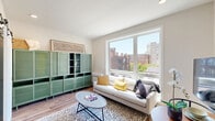 Located at 1314 Spring Garden St in Philadelphia's Spring Garden neighborhood, this efficiently designed one-bedroom, one-bathroom unit makes excellent use of its compact footprint across a single floor. The open layout maximizes functionality without sacrificing style, featuring warm hardwood-style flooring and a neutral color palette throughout.

The kitchen is a standout feature, outfitted with sleek gray wood-grain cabinetry, light quartz countertops, a white subway tile backsplash, and stainless steel appliances including an induction cooktop, wall oven, and dishwasher. Open shelving adds both storage and visual interest to the space.

The bedroom is thoughtfully designed with built-in floor-to-ceiling cabinetry and open shelving flanking the bed, providing ample storage within a cozy footprint. A doorway directly connects to the bathroom, enhancing convenience. Large windows in the living area invite natural light and offer city views of the Philadelphia skyline.

The bathroom features large-format tile flooring, a floating vanity with a rectangular vessel sink, a wide backlit mirror, and a clean, modern aesthetic. The overall ambiance of the unit is contemporary and streamlined, reflecting a practical yet polished approach to urban living in one of Philadelphia's vibrant neighborhoods.