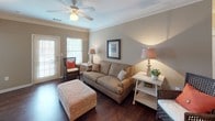 This single-floor residence offers a thoughtfully designed layout with a warm, cohesive aesthetic throughout. The living room serves as the heart of the home, featuring rich hardwood flooring, crown molding, a ceiling fan, and a glass-paneled door that invites natural light into the space. The adjacent dining area continues the hardwood flooring and is accented by crown molding and a pendant light fixture overhead. The kitchen is equipped with dark cabinetry, granite-style countertops, black appliances including a refrigerator, stove, and microwave, and a peninsula breakfast bar that provides additional prep and seating space. A hallway connects the main living areas to the private quarters. The space includes multiple bedrooms, each finished with plush carpeting and ceiling fans or overhead lighting. The primary bedroom features soft blue walls, dual windows for natural light, and a walk-in closet. Additional bedrooms offer neutral tones, ample natural light, and closet access. Two bathrooms are present: one with a tub-shower combination and granite-topped dark vanity with hardwood flooring, and a second with a similar vanity and coordinating finishes. The overall ambiance is warm, comfortable, and move-in ready.