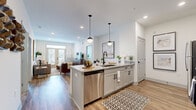 This thoughtfully designed single-floor residence offers two bedrooms and two bathrooms within a well-utilized floor plan. The open-concept kitchen and living area serves as the heart of the home, where warm hardwood-style flooring, recessed lighting, and crisp white walls create a bright, contemporary atmosphere. The kitchen is outfitted with granite countertops, gray shaker-style cabinetry with matte black hardware, a subway tile backsplash, stainless steel appliances, and a central island with pendant lighting—ideal for both cooking and casual dining. The living area flows naturally from the kitchen and features French doors topped with a transom window, filling the space with natural light and providing access to an outdoor area. The primary bedroom is generously sized with plush carpeting, multiple windows, a ceiling fan, and direct access to both a private bathroom and a walk-in closet equipped with wire shelving systems. The second bedroom mirrors the comfortable, light-filled aesthetic. The bathrooms feature granite-topped vanities, gray cabinetry, and wood-look tile flooring, maintaining the consistent, modern design language found throughout the residence.