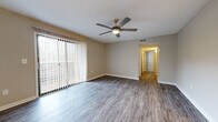 Located in Ridgeland, Mississippi, this 2-bedroom, 2-bathroom single-story residence offers a well-organized layout designed for comfortable everyday living. The living room is a welcoming, open space highlighted by durable wood-look flooring, a ceiling fan with light fixture, a textured ceiling, and a large sliding glass door dressed with vertical blinds that fill the room with natural light. A hallway connects the living area to the rest of the home. The galley-style kitchen is efficiently designed with ample gray cabinetry on both sides, light-toned countertops, wood-look flooring, and stainless steel appliances including an electric range and refrigerator. A pendant chandelier illuminates the adjacent dining area. The primary bedroom offers generous proportions, plush carpeting, a ceiling fan, a closet, and direct access to a private bathroom. The second bedroom also features carpeting, a ceiling fan, and a window that brings in natural light. Two hallways guide circulation throughout the home, connecting the bedrooms, bathrooms, and main living spaces. The neutral, warm-toned walls and consistent flooring choices throughout create a cohesive and clean aesthetic, making this a practical and move-in-ready residence.