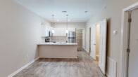 Located at 4637 Sara Rd in Valdosta, Georgia, this single-story home presents a clean, neutral aesthetic with a practical and open layout. Wood-look flooring runs consistently throughout the living spaces, lending warmth and visual continuity across the home.

The kitchen serves as a focal point of the interior, designed with white shaker-style cabinetry, light stone-look countertops, and a full suite of stainless steel appliances including a refrigerator, range, and microwave. A peninsula with an integrated sink extends into the living area, creating a natural gathering point and enhancing the open-concept flow. Pendant lighting above the peninsula adds a polished finishing touch.

The living and dining areas are generously proportioned, featuring ceiling fans and neutral beige walls that provide a versatile backdrop. Natural light enters through windows fitted with blinds, brightening the space without sacrificing privacy. The entryway is defined by a classic six-panel door and offers a welcoming transition into the main living area.

Bedrooms continue the home's consistent flooring and neutral palette, each equipped with ceiling fans and windows for natural ventilation and light. The bathrooms feature tub-shower combinations with clean white surrounds and chrome fixtures, maintaining the home's straightforward, functional character throughout.