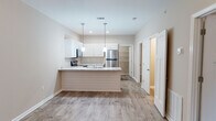 Located at 4637 Sara Rd in Valdosta, Georgia, this single-story home presents a clean, neutral aesthetic with a practical and open layout. Wood-look flooring runs consistently throughout the living spaces, lending warmth and visual continuity across the home.

The kitchen serves as a focal point of the interior, designed with white shaker-style cabinetry, light stone-look countertops, and a full suite of stainless steel appliances including a refrigerator, range, and microwave. A peninsula with an integrated sink extends into the living area, creating a natural gathering point and enhancing the open-concept flow. Pendant lighting above the peninsula adds a polished finishing touch.

The living and dining areas are generously proportioned, featuring ceiling fans and neutral beige walls that provide a versatile backdrop. Natural light enters through windows fitted with blinds, brightening the space without sacrificing privacy. The entryway is defined by a classic six-panel door and offers a welcoming transition into the main living area.

Bedrooms continue the home's consistent flooring and neutral palette, each equipped with ceiling fans and windows for natural ventilation and light. The bathrooms feature tub-shower combinations with clean white surrounds and chrome fixtures, maintaining the home's straightforward, functional character throughout.