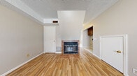 This two-story home in Emporia, Kansas, efficiently distributes its living space across two equally sized floors, offering a well-organized layout that includes two bedrooms, a living room, kitchen, dining room, entrance, hallway, and a closet. The main floor welcomes residents through a dedicated entrance that flows into the living areas. The living room is a notable highlight, featuring a tile-surround fireplace, warm hardwood-style flooring, and a textured ceiling with an angled architectural detail above the fireplace that adds visual interest. Adjacent to the living room, the kitchen is equipped with dark gray cabinetry, tile backsplash, light tile flooring, a double sink, and white appliances including a refrigerator, range, microwave, and dishwasher. A door in the kitchen provides convenient exterior access with natural light from a window. The dining room features light tile flooring, maintaining a cohesive aesthetic with the kitchen. Upstairs, the two bedrooms offer a mix of carpet and hardwood-style flooring. The primary bedroom is generously sized and includes a sliding-door closet with a built-in rod. Both bedrooms feature windows that allow natural light and outdoor views. Neutral tones throughout create a calm, functional atmosphere.
