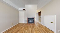 This two-story home in Emporia, Kansas, efficiently distributes its living space across two equally sized floors, offering a well-organized layout that includes two bedrooms, a living room, kitchen, dining room, entrance, hallway, and a closet. The main floor welcomes residents through a dedicated entrance that flows into the living areas. The living room is a notable highlight, featuring a tile-surround fireplace, warm hardwood-style flooring, and a textured ceiling with an angled architectural detail above the fireplace that adds visual interest. Adjacent to the living room, the kitchen is equipped with dark gray cabinetry, tile backsplash, light tile flooring, a double sink, and white appliances including a refrigerator, range, microwave, and dishwasher. A door in the kitchen provides convenient exterior access with natural light from a window. The dining room features light tile flooring, maintaining a cohesive aesthetic with the kitchen. Upstairs, the two bedrooms offer a mix of carpet and hardwood-style flooring. The primary bedroom is generously sized and includes a sliding-door closet with a built-in rod. Both bedrooms feature windows that allow natural light and outdoor views. Neutral tones throughout create a calm, functional atmosphere.